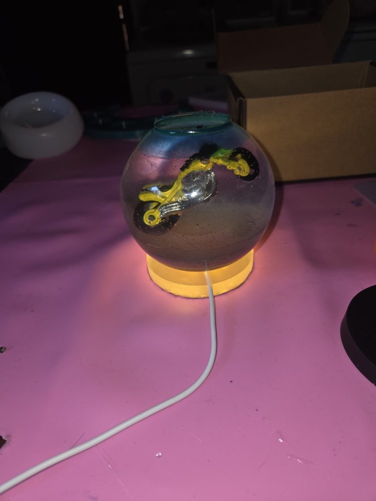 Light-up resin sphere with an embedded dirt bike on a glowing amber base